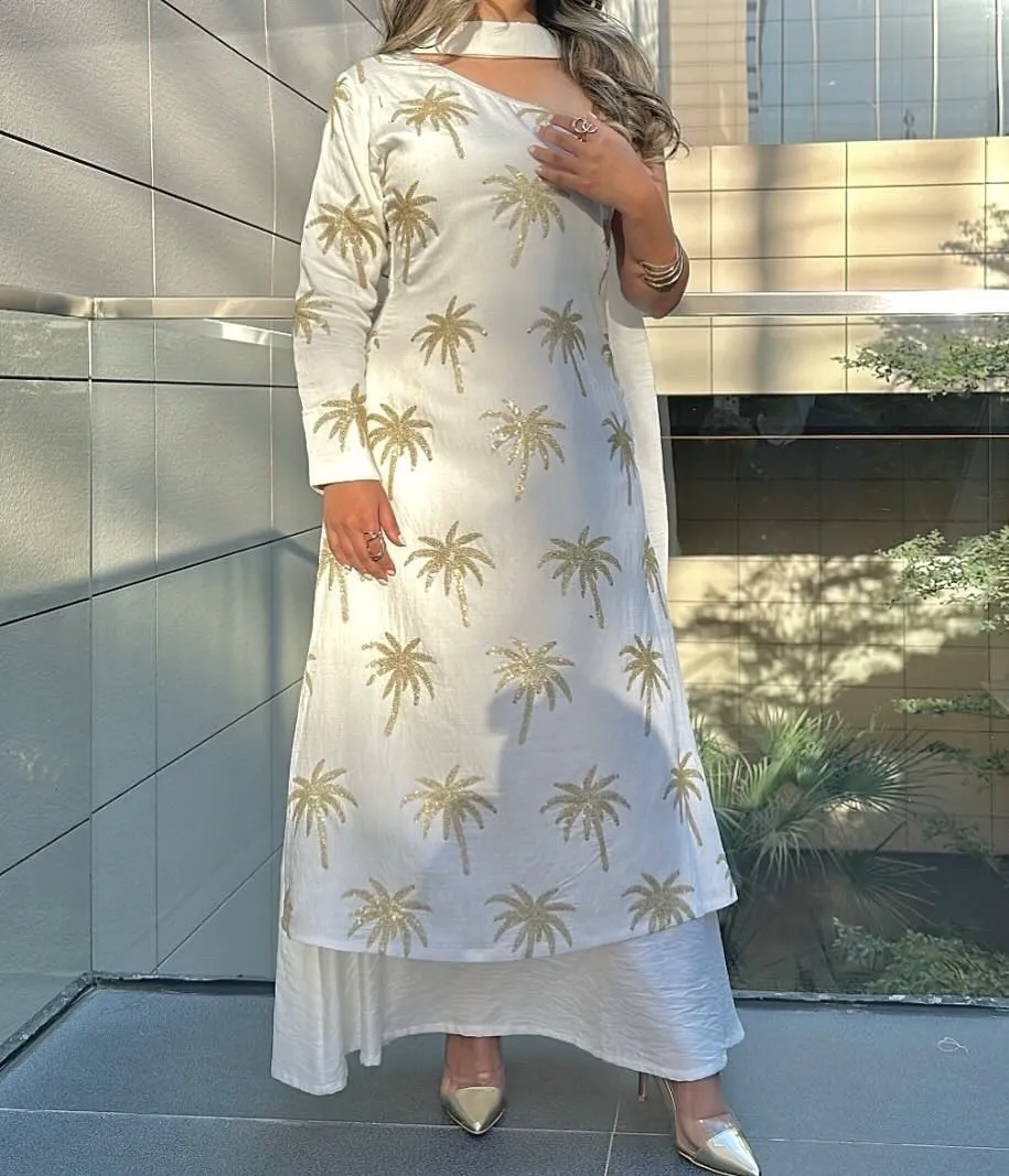 Ivory long dress with gold palm tree embroidery, layered over a long skirt