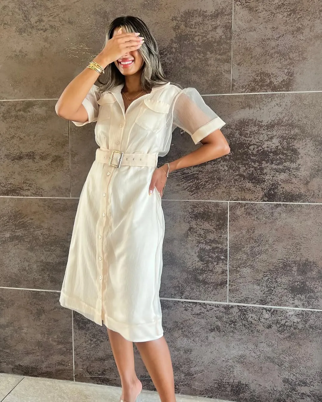 Belted organza shirt dress in ivory against a dark stone wall