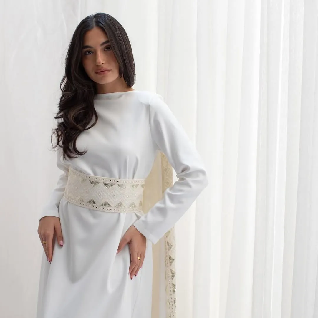 Ivory dress with an embroidered belt, white curtains behind